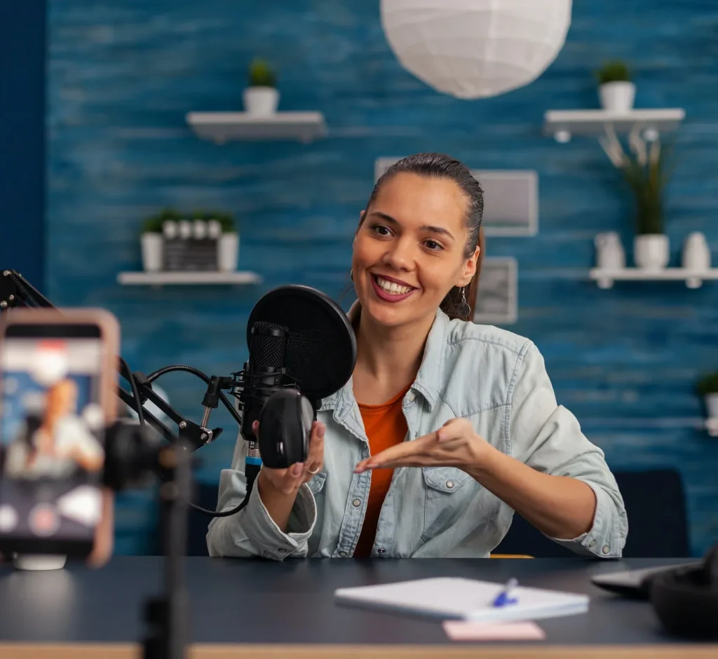 smiling influencer recording mouse review with smartphone